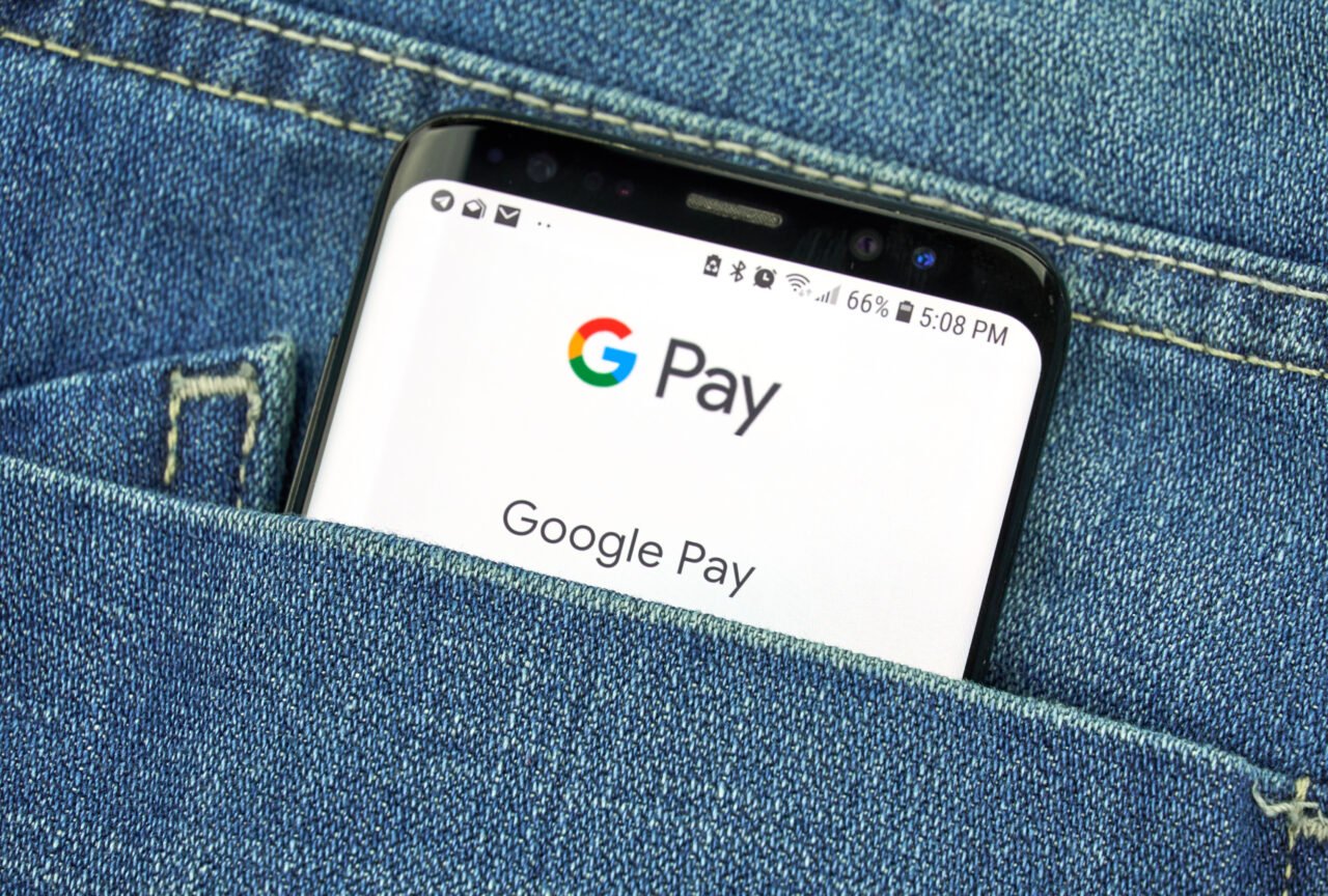 Smartfon w tylnej kieszeni dżinsów z wyświetloną aplikacją Google Pay.