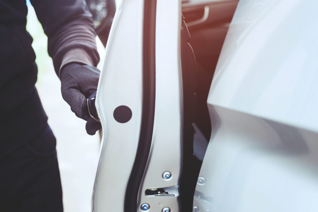 Eksperci przestrzegają, że choć metoda na kradzież samochodu bez kluczyka na wcale nie jest nowa, można zastosować nietypową ochronę, aby zapobiegać takim incydentom. Mężczyzna w rękawiczkach otwiera drzwi białego samochodu.