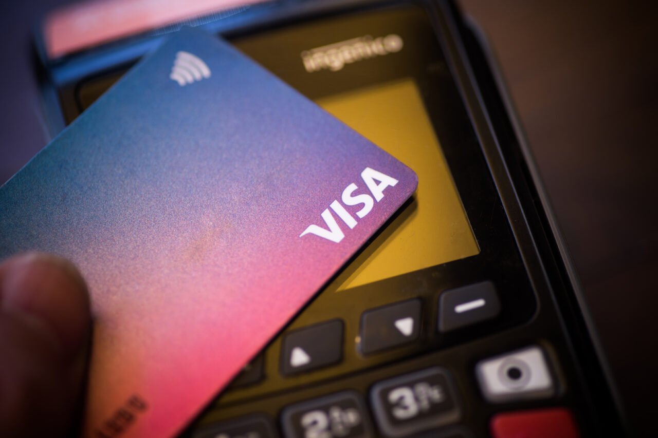 Zbliżenie na kartę Visa i terminal płatniczy.