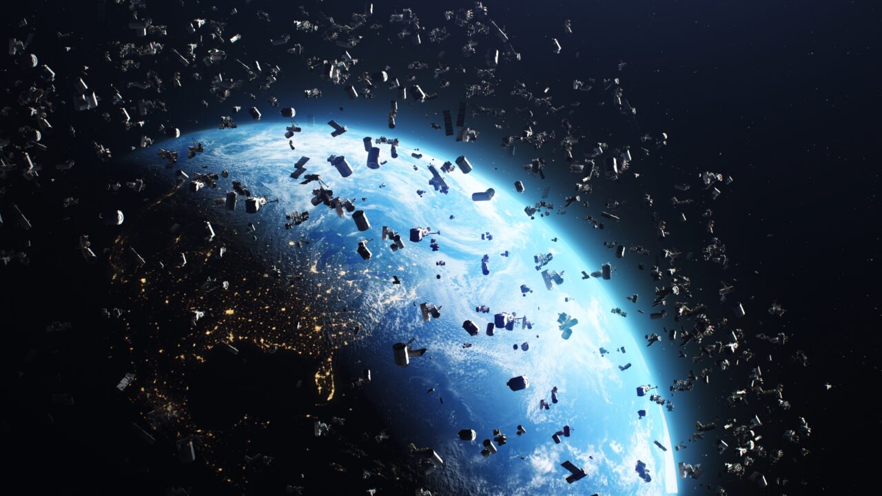 Zdjęcie ilustrujące Ziemię z kosmosu otoczoną przez odpady kosmiczne, z widocznymi światłami miast na nocnym półkuli.