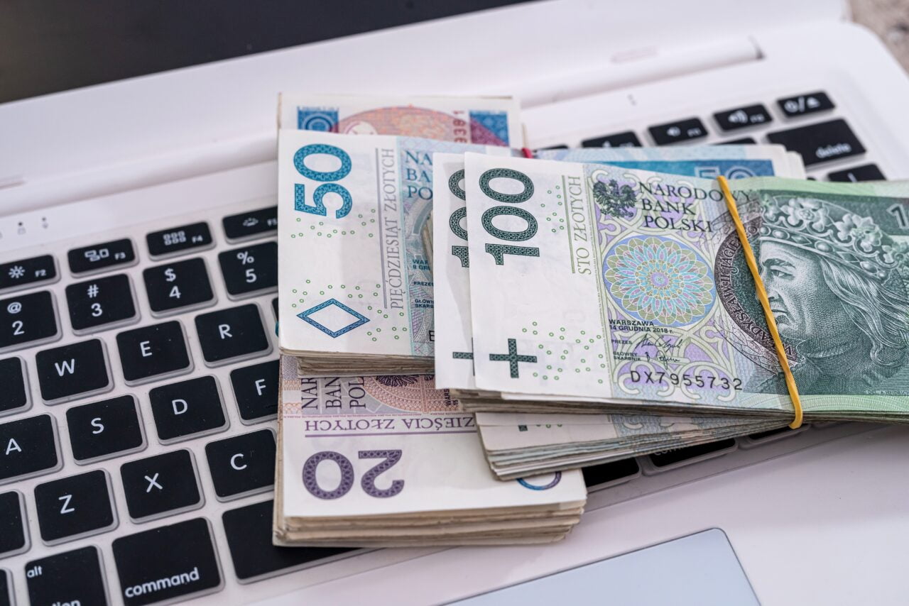 Stosy polskich banknotów na klawiaturze laptopa.