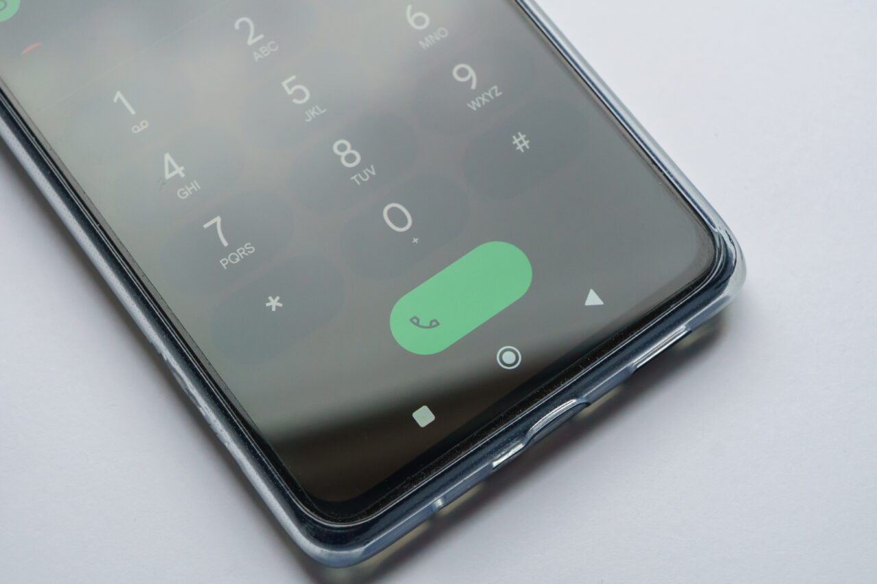 Telefon komórkowy przedstawiający ekran z wyświetlanym interfejsem wybierania numeru i zielonym przyciskiem do rozpoczęcia połączenia.