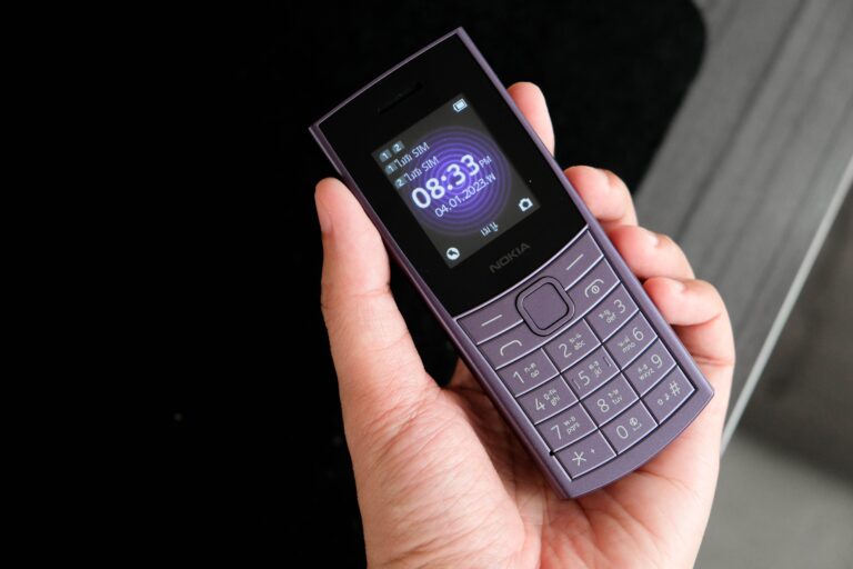 Dłoń trzymająca telefon komórkowy marki Nokia na czarnym tle.