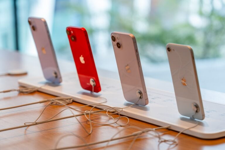 Cztery iPhone'y w różnych kolorach na wystawie w sklepie.