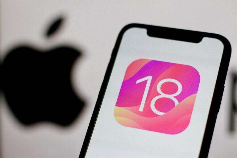 Telefon iPhone z wyświetlonym logo ios 18 systemu operacyjnego iOS 18, w tle rozmyte logo Apple.