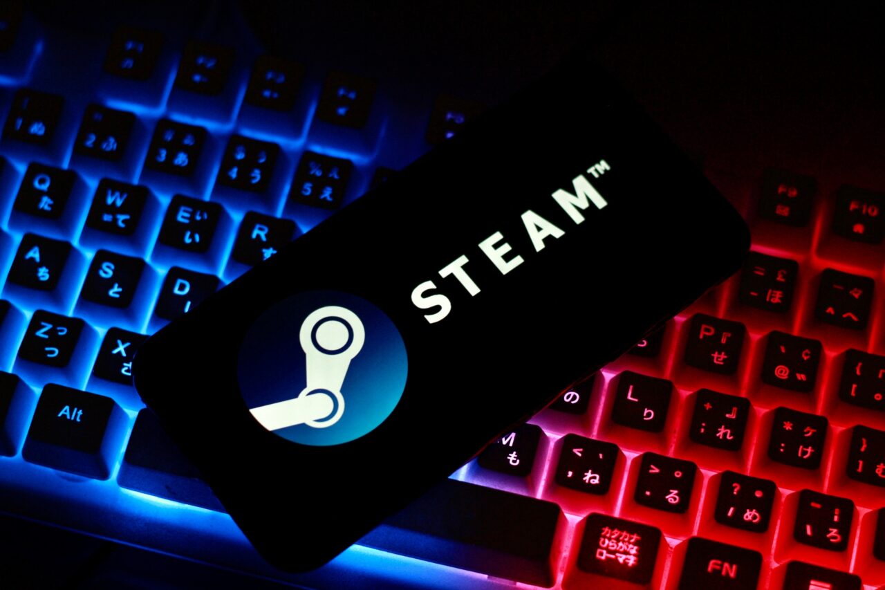 Petycja do platformy Steam. Smartfon z logo Steam na podświetlanej klawiaturze komputerowej.