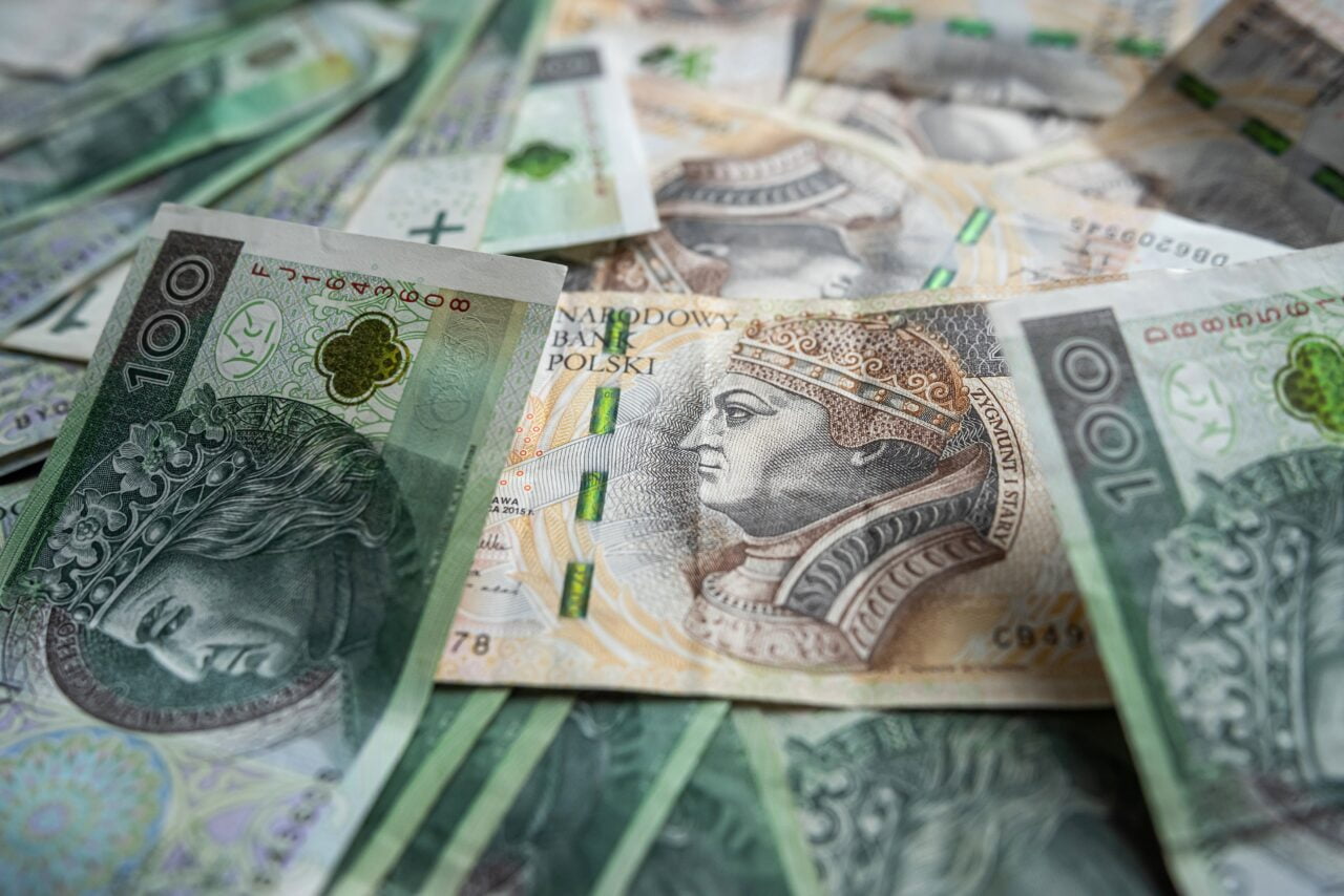 Rozproszone banknoty polskie o różnych nominałach, w tym widoczny banknot 100-złotowy.
