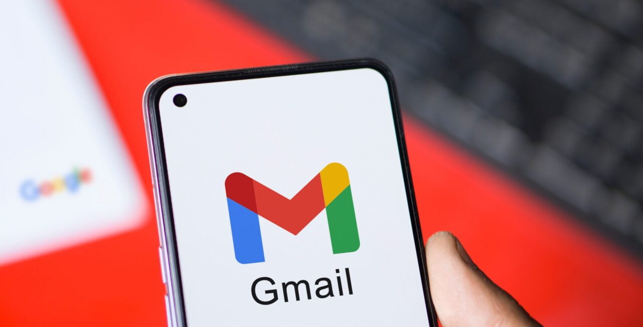 Widok smartfona z otwartą aplikacją Gmail, w tle klawiatura i logo Google.