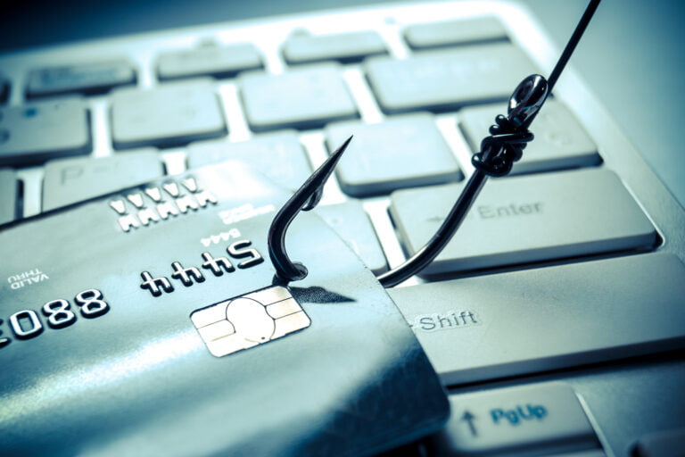 Haczyk na żyłce leżący na karcie kredytowej umieszczonej na klawiaturze komputera, symbolizujący zagrożenia cyberprzestępczości.
