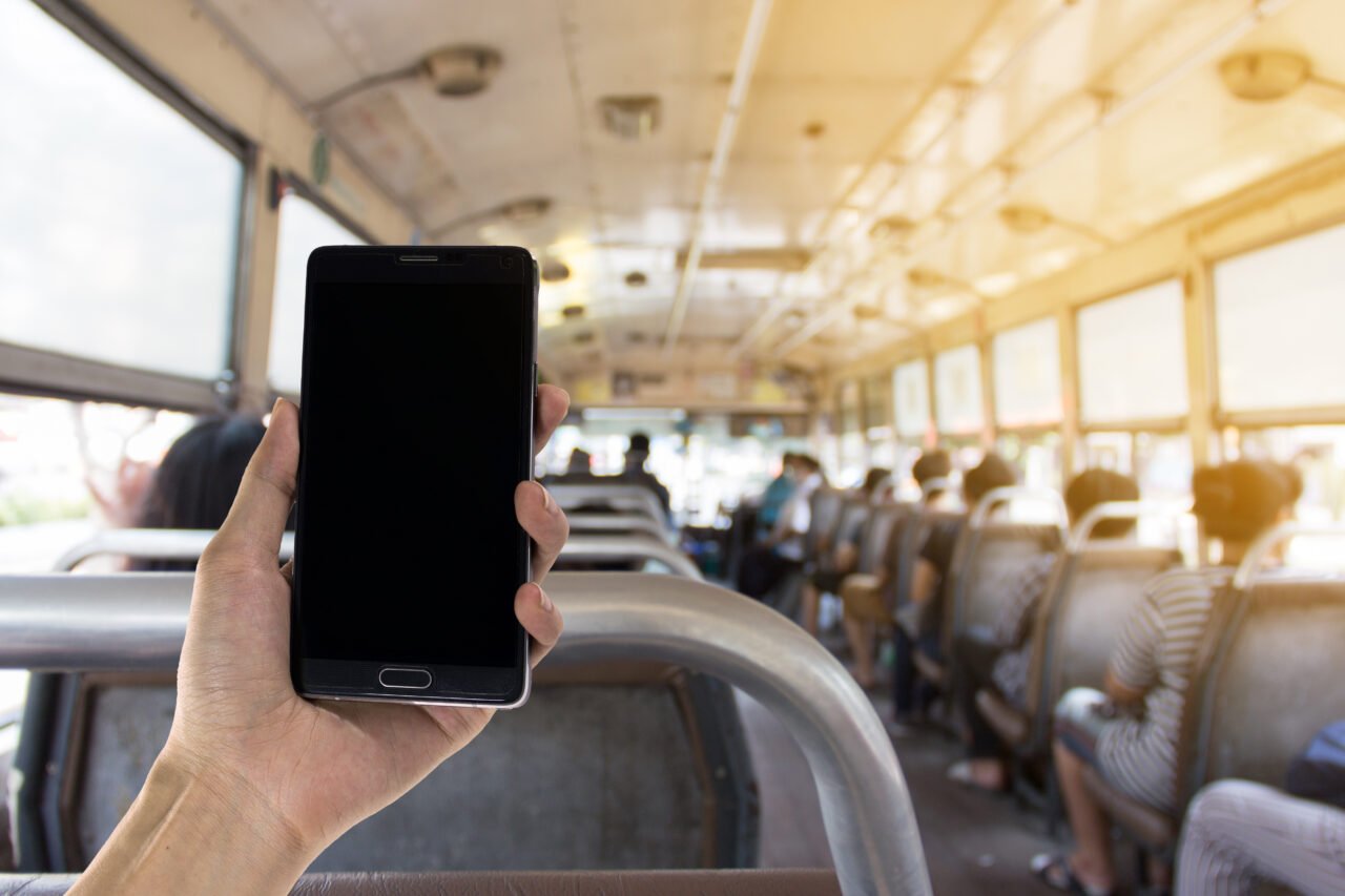 Bilet w aplikacji Ręka trzymająca smartfon w autobusie miejskim.