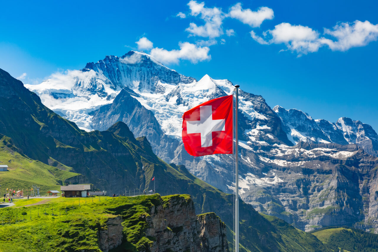 Flaga Szwajcarii na tle śnieżnych szczytów Alp. Tylko ten graj ma wyższe ceny gier niż polski Steam