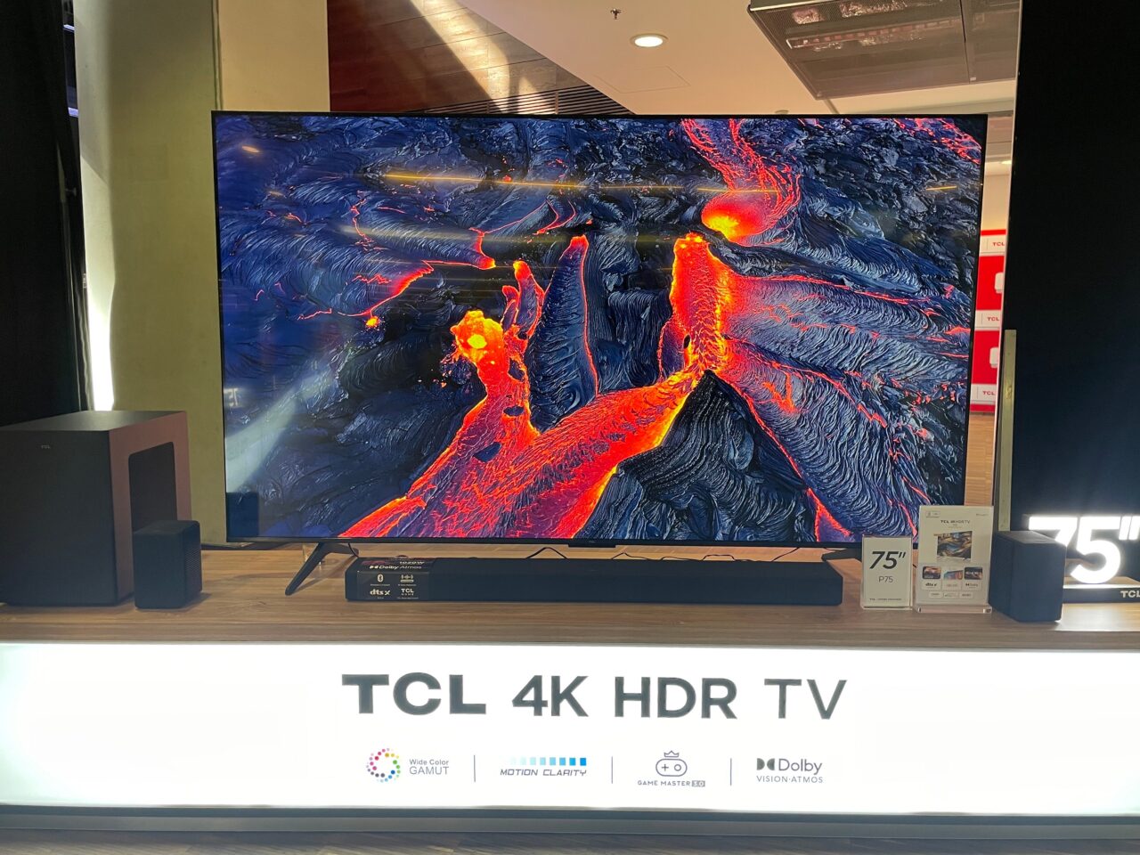 Telewizor TCL 4K HDR 75 cali prezentujący obraz lawy płynącej przez skaliste tereny.