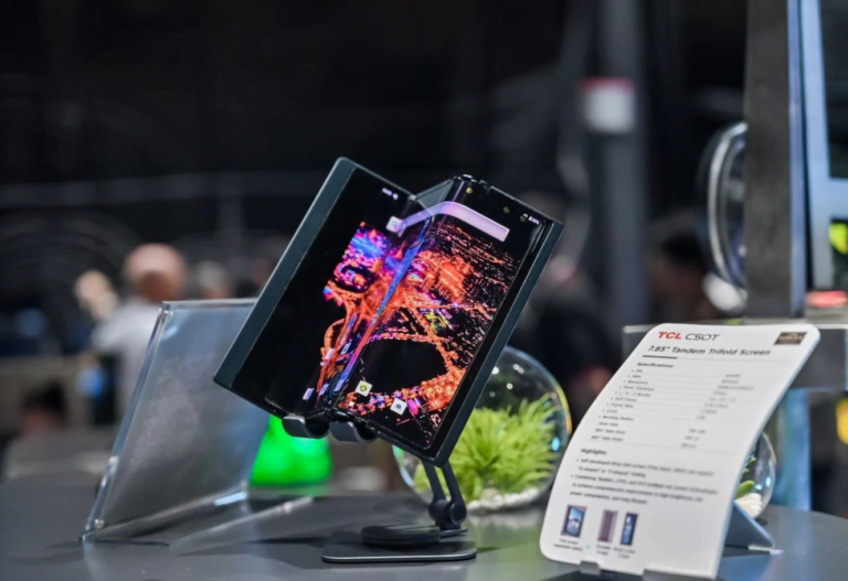 Złożony smartfon z giętkim ekranem na stojaku wystawowym obok tabliczki informacyjnej z danymi technicznymi.