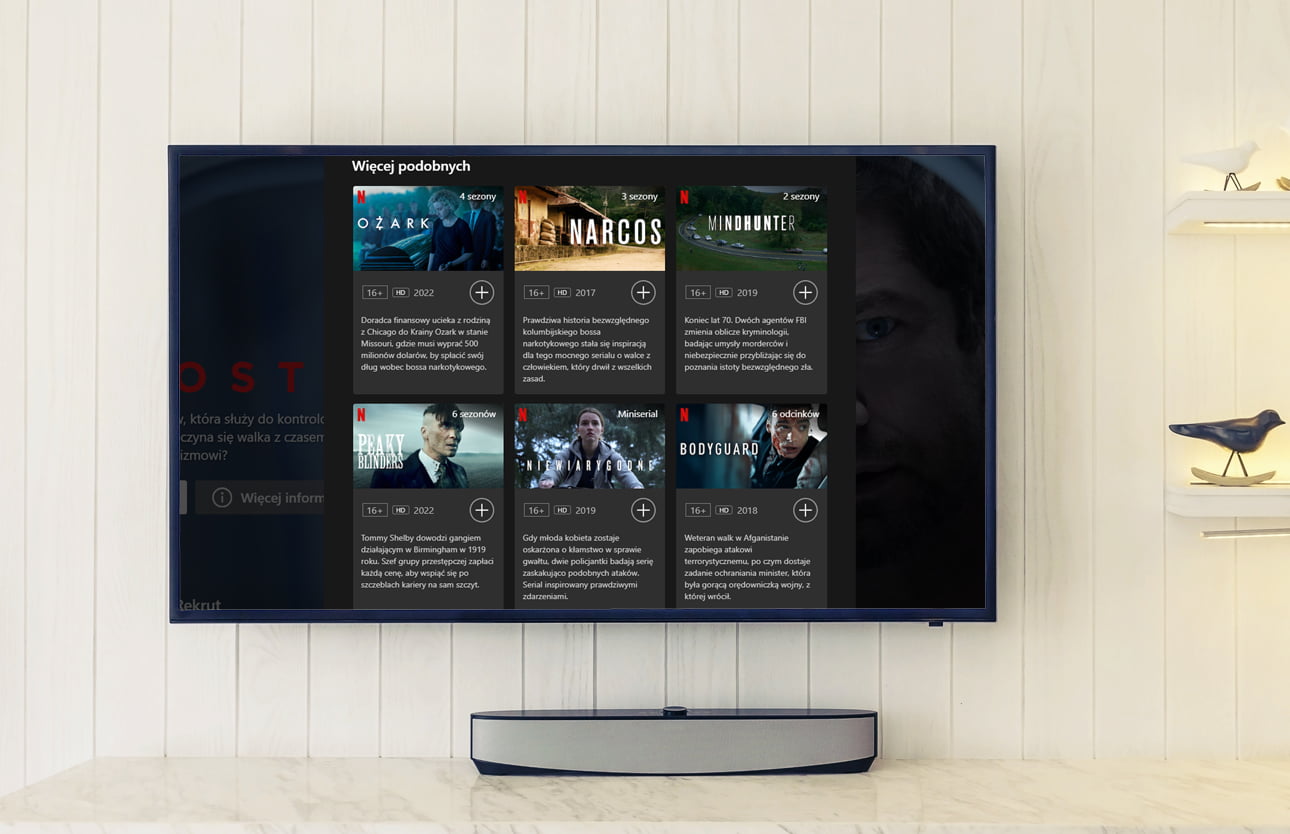 Telewizor na ścianie z wyświetlonym interfejsem Netflix, pokazujący propozycje seriali takich jak Ozark, Narcos, Mindhunter, Peaky Blinders, Niewiarygodne i Bodyguard.