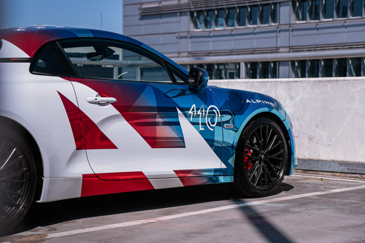 Test Alpine A110 S, samochód sportowy na parkingu z kolorowym malowaniem.