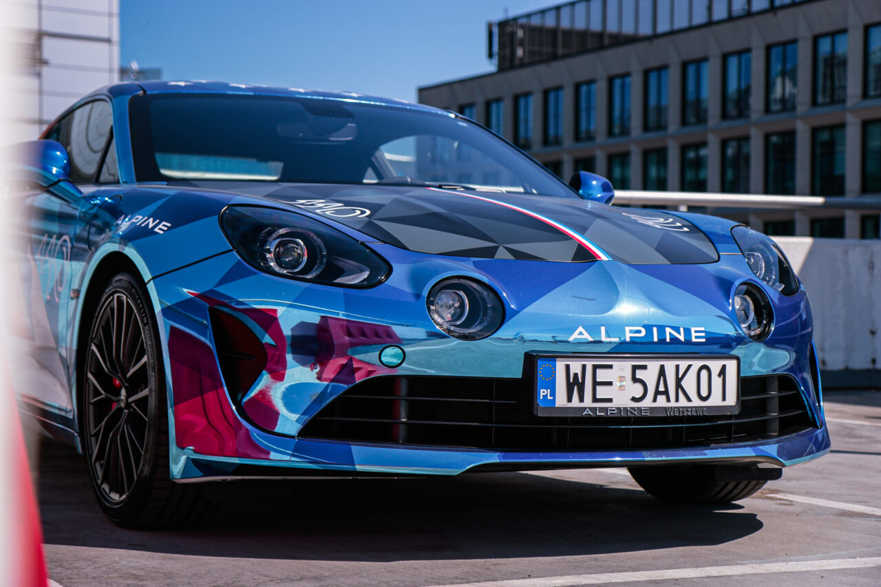 Test Alpine A110 S, przód niebieskiego sportowego samochodu na parkingu.