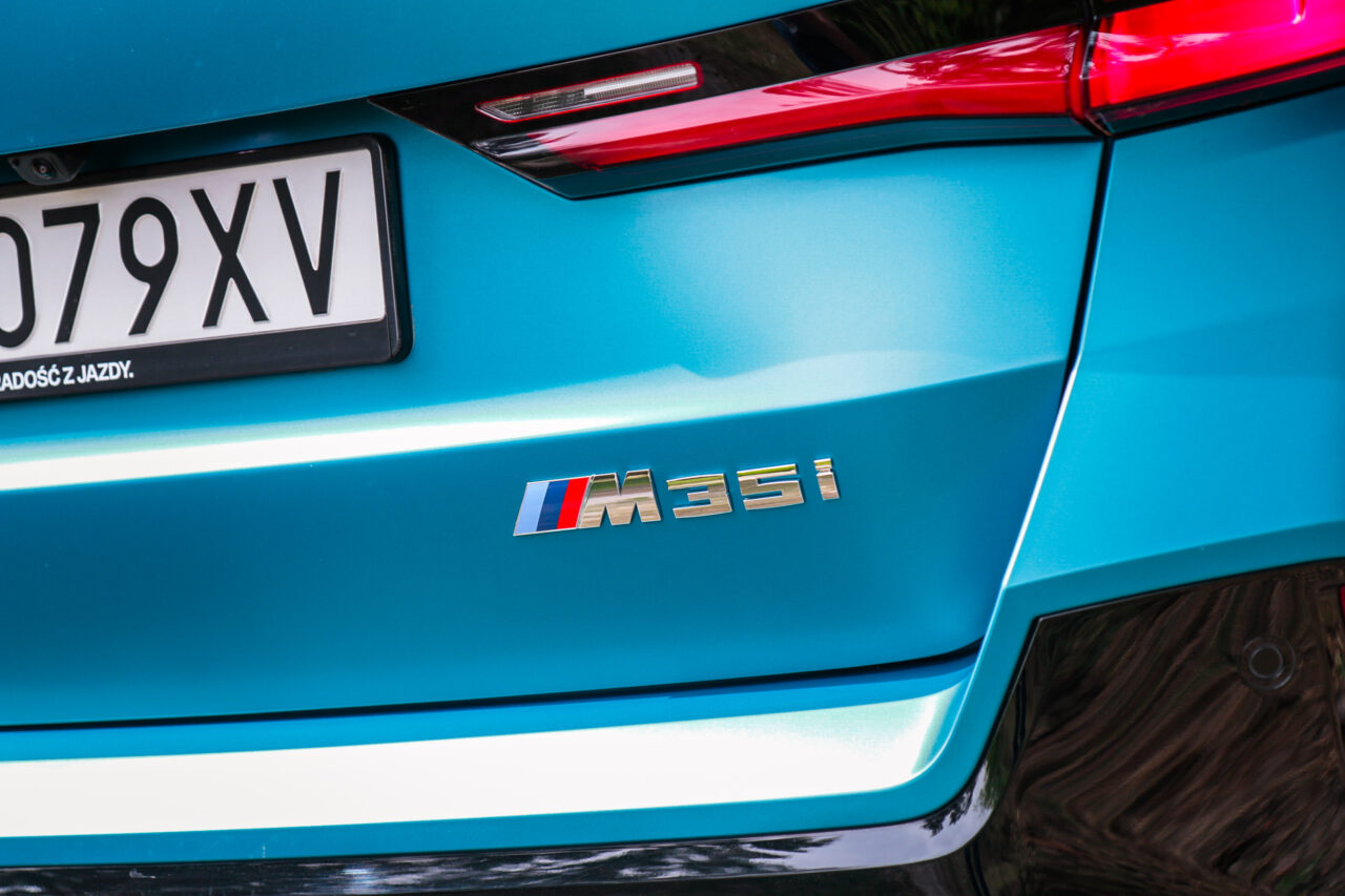 Zbliżenie na emblemat M35i na tylnej części błękitnego BMW X1 M35i.