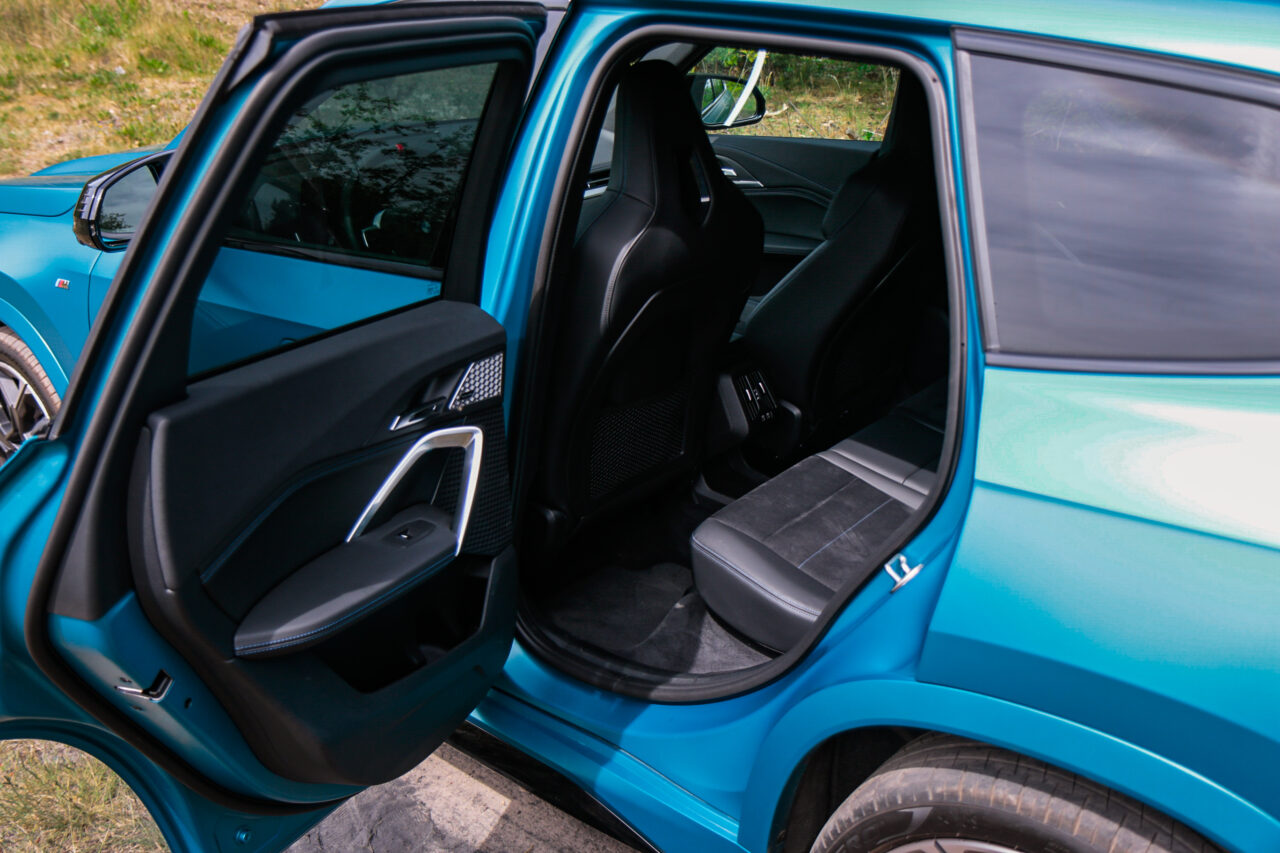 Wnętrze BMW X1 M35i z otwartymi przednimi i tylnymi drzwiami, pokazujące nowoczesne wykończenie i sportowe fotele.