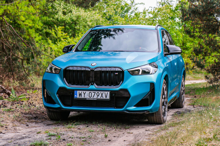 Test BMW X1 M35i na leśnej drodze, widok z przodu na niebieski samochód.