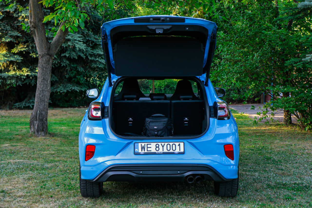 Niebieski Ford Puma ST X z otwartym bagażnikiem na tle drzew, test Ford Puma ST X.