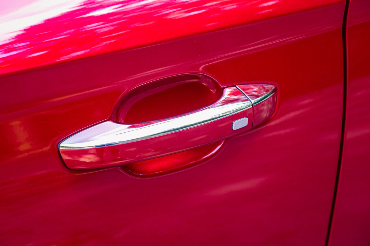 Czerwony samochód z widoczną chromowaną klamką drzwi, test MG ZS.