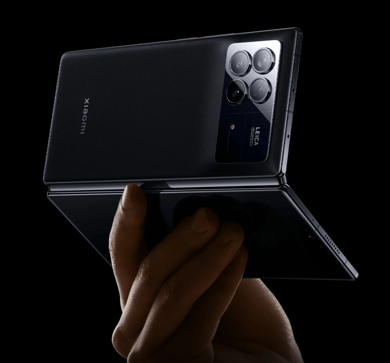 Składany smartfon trzymany w dłoni, z widocznym logo Leica i potrójnym układem aparatu na tylnej obudowie.