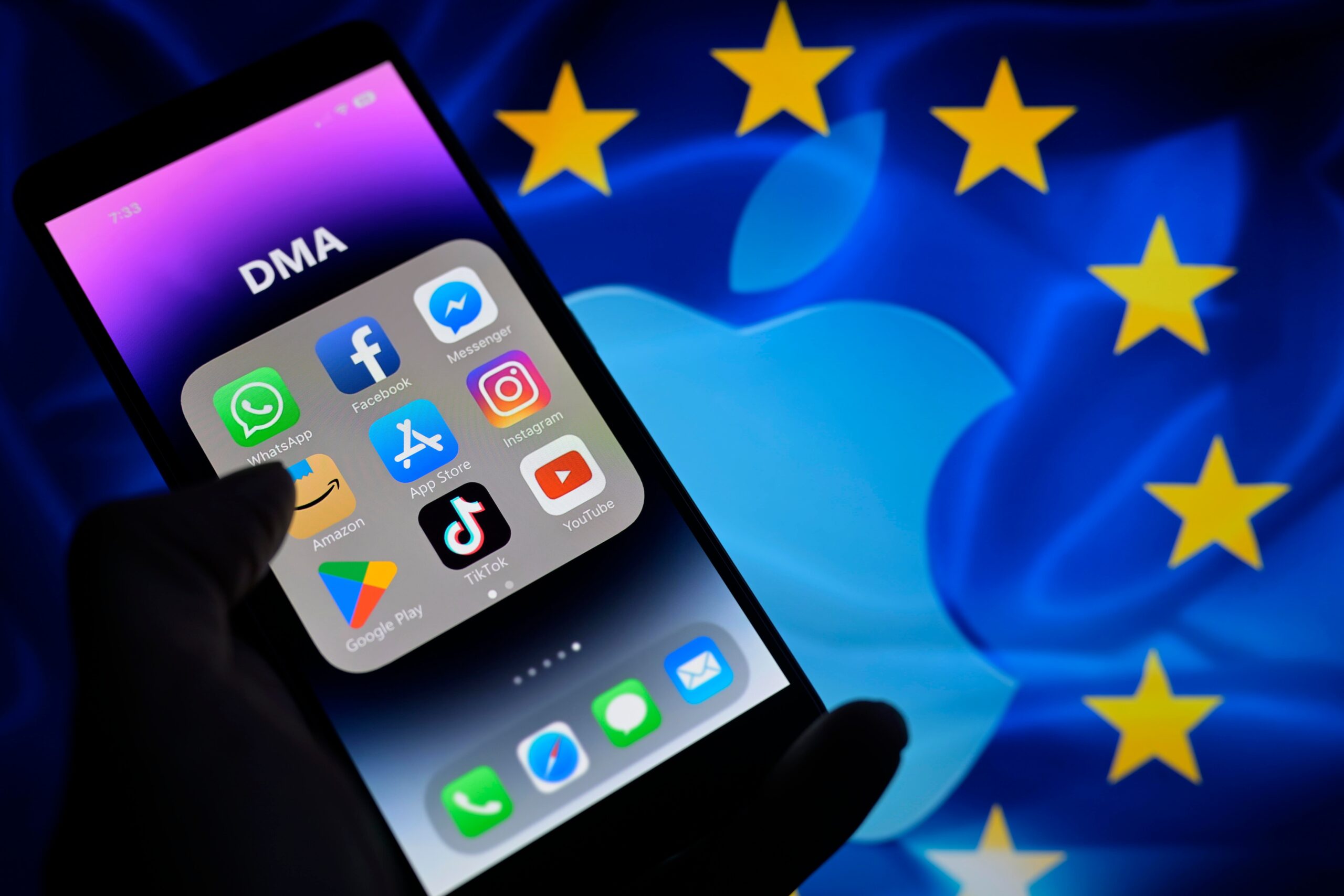 Smartfon z otwartym folderem aplikacji, w tle flaga Unii Europejskiej z logo Apple.