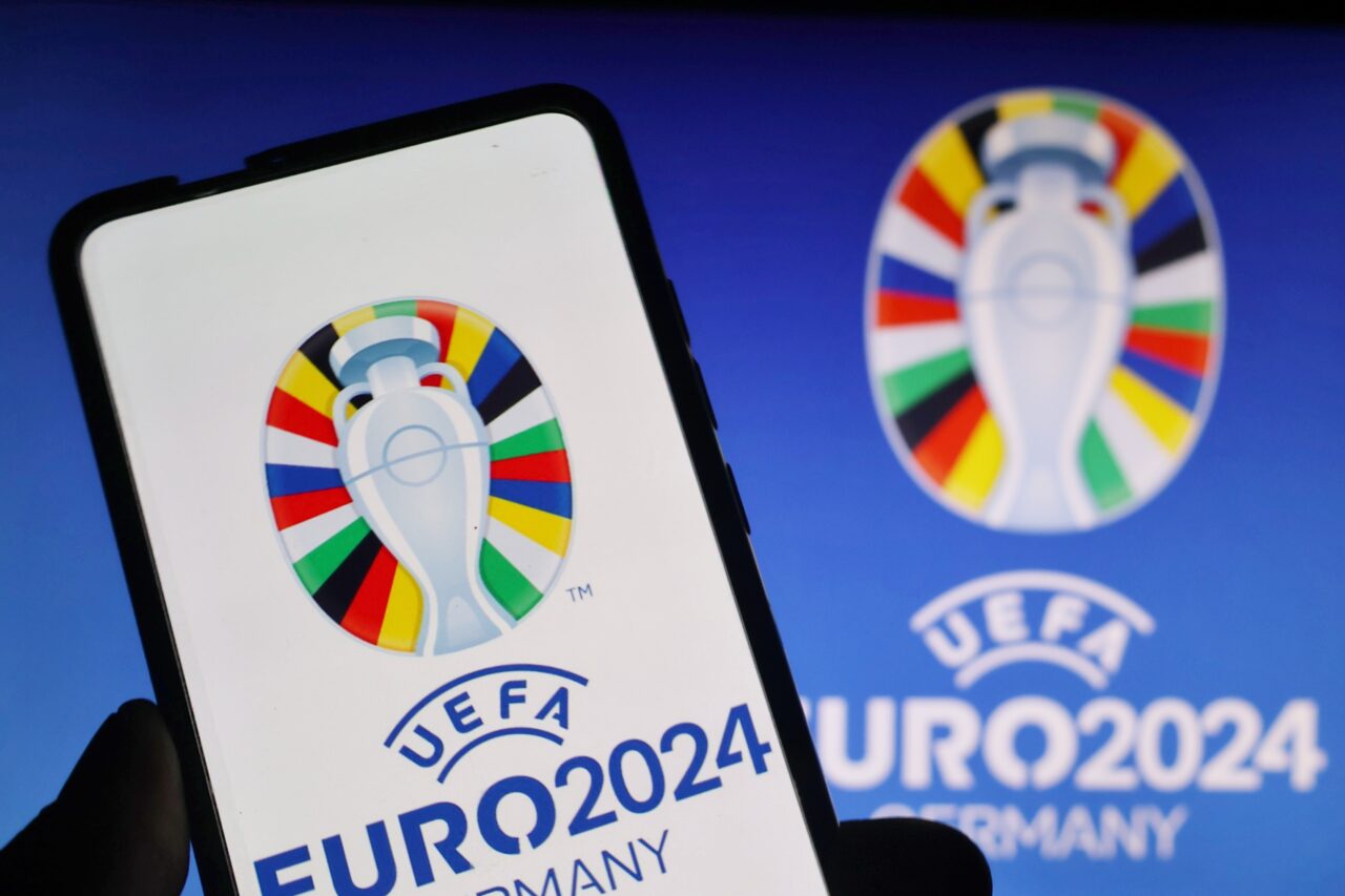 Logo UEFA Euro 2024 na ekranie telefonu komórkowego z wielokolorowym tłem.