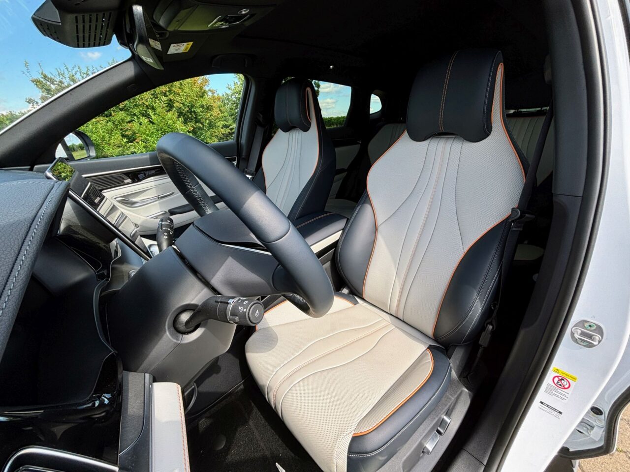 Wnętrze nowoczesnego samochodu BYD z jasnymi skórzanymi fotelami i czarnymi detalami.