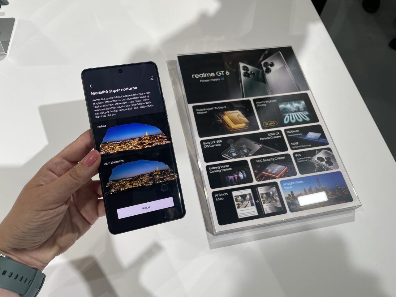 Osoba trzymająca telefon realme GT 6 promujący tryb Super nocny przy ekspozycji smartfona Realme GT 6 z opisanymi cechami technicznymi.