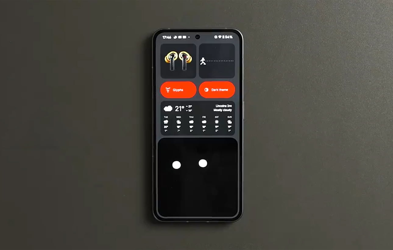 Smartfon z ekranem głównym z różnymi widgetami, w tym informacją o pogodzie, słuchawkami oraz ikonami do zmiany motywu.