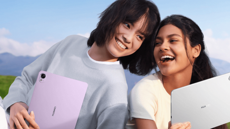 Dwie uśmiechnięte osoby trzymające tablety Huawei na tle natury.