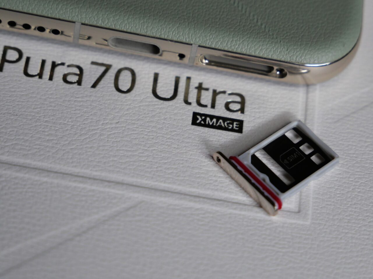 Górna część telefonu Pura70 Ultra na białym tle z wyciągniętym slotem na kartę SIM.
