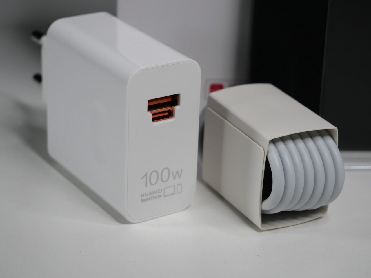 Biała ładowarka Huawei 100W SuperCharge z portem USB-C i zwinięty kabel.