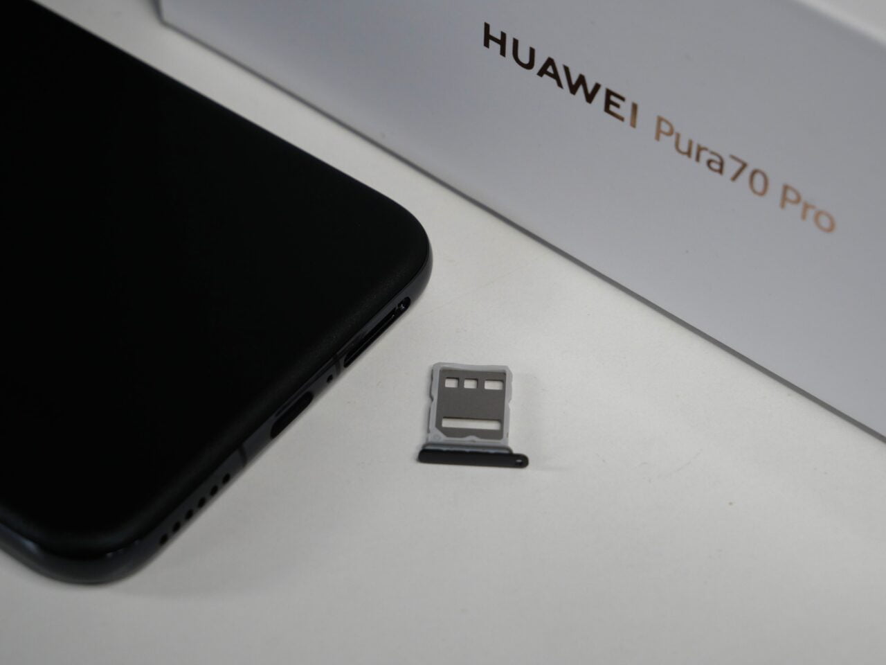 Czarny smartfon, tacka na karty SIM i karta microSD oraz pudełko z napisem "HUAWEI Pura70 Pro".