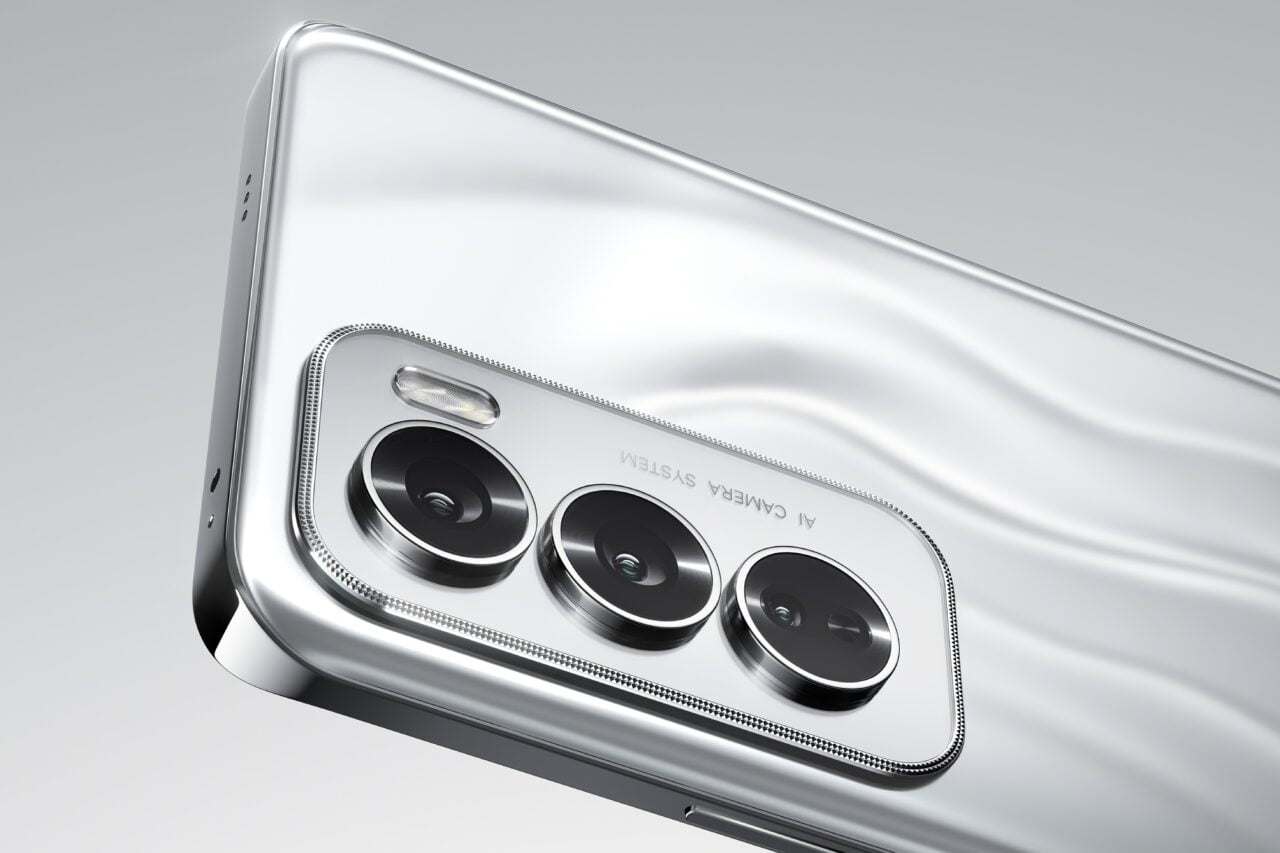 Srebrny smartfon widziany od tyłu, z trzema aparatami i lampą błyskową.