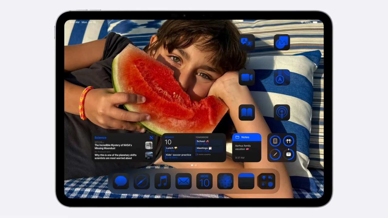 Tablet z ekranem głównym pokazującym dziecko jedzące arbuza, z ikonami i widżetami aplikacji na ekranie.