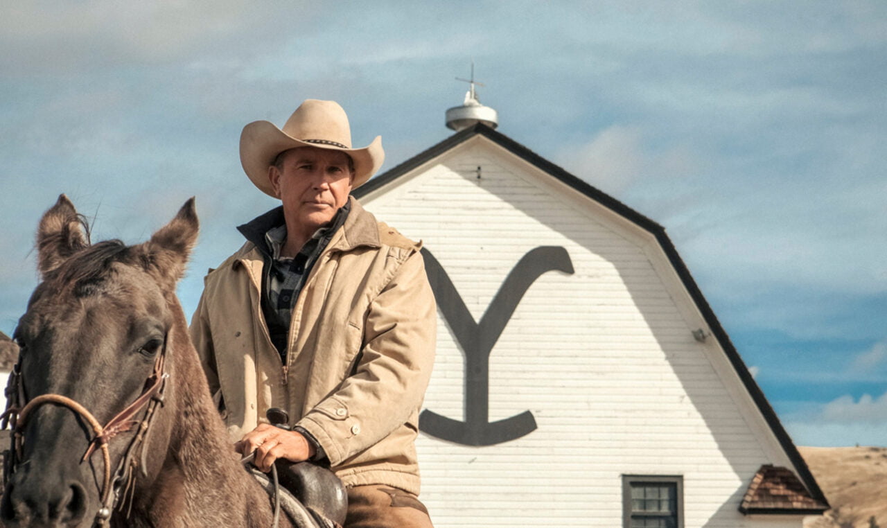 Yellowstone w telewizji. Kowboj na koniu przed białą stodołą z logo "Y".