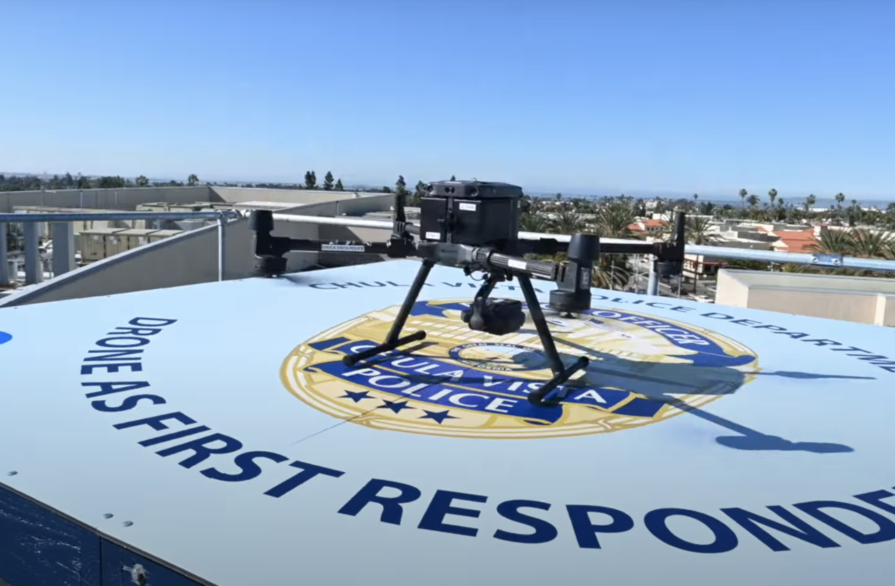 Dron stojący na podeście z napisem "DRONE AS FIRST RESPONDER" oraz logo i nazwą "Chula Vista Police Department".
