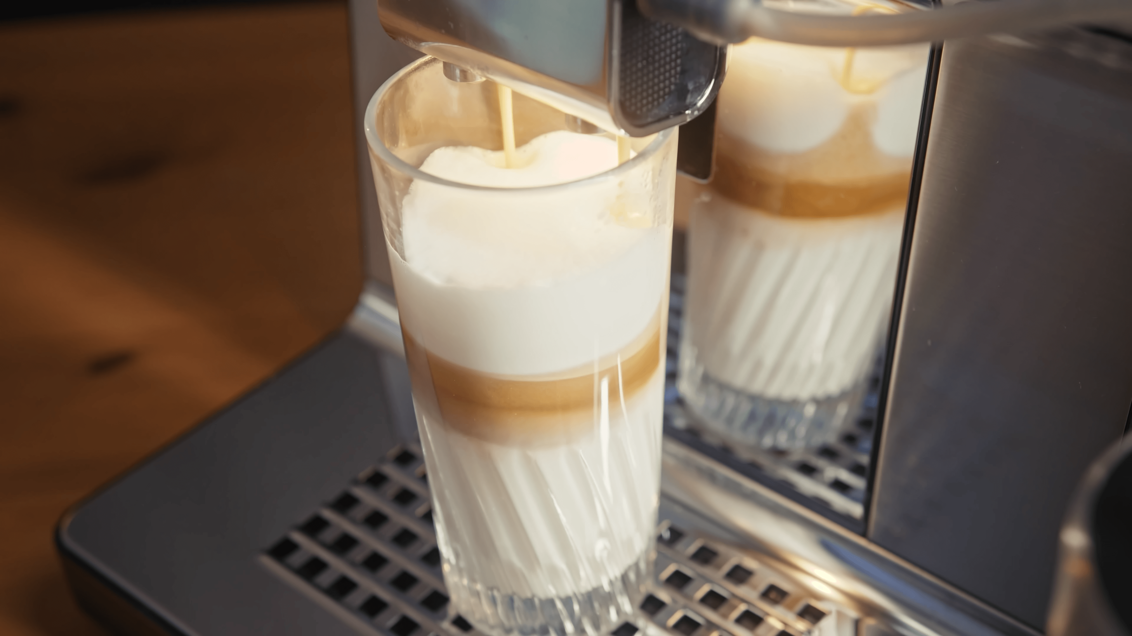 Szklanka latte macchiato przygotowywanego w ekspresie do kawy.