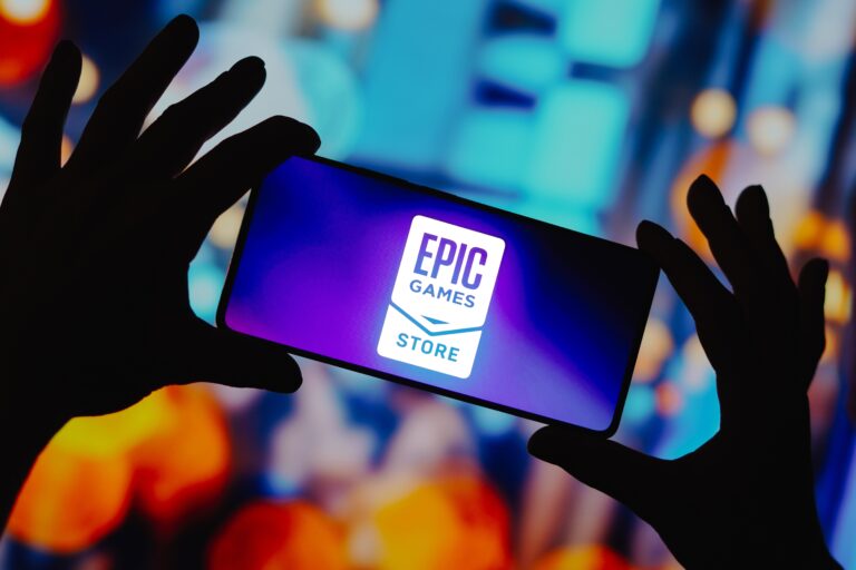 Telefon trzymany w dłoniach, wyświetlający logo Epic Games Store na rozmytym, kolorowym tle. Wyciek potwierdził Red Dead Redemption na PC