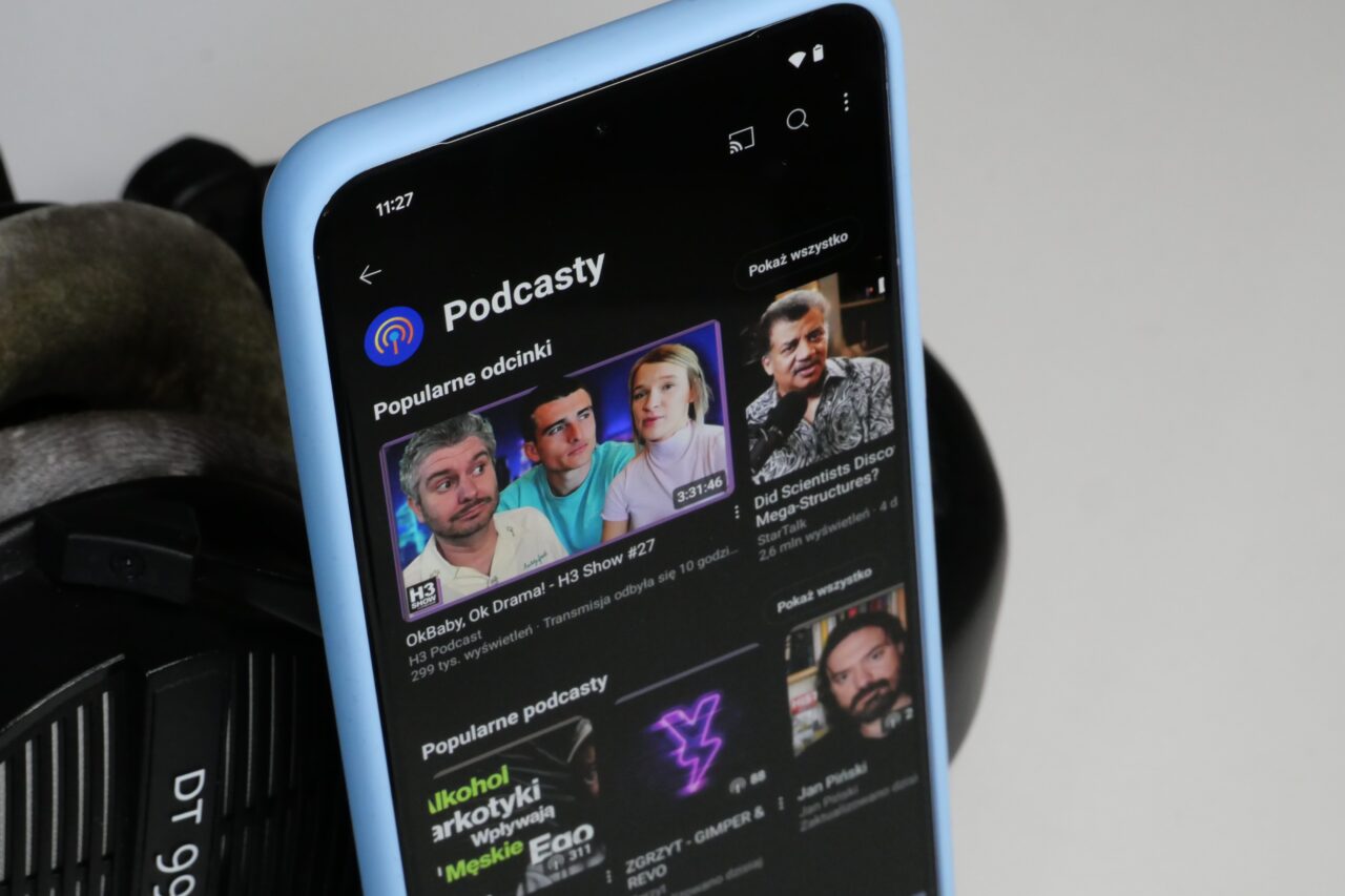 Smartfon z aplikacją podcastową wyświetlającą popularne odcinki.