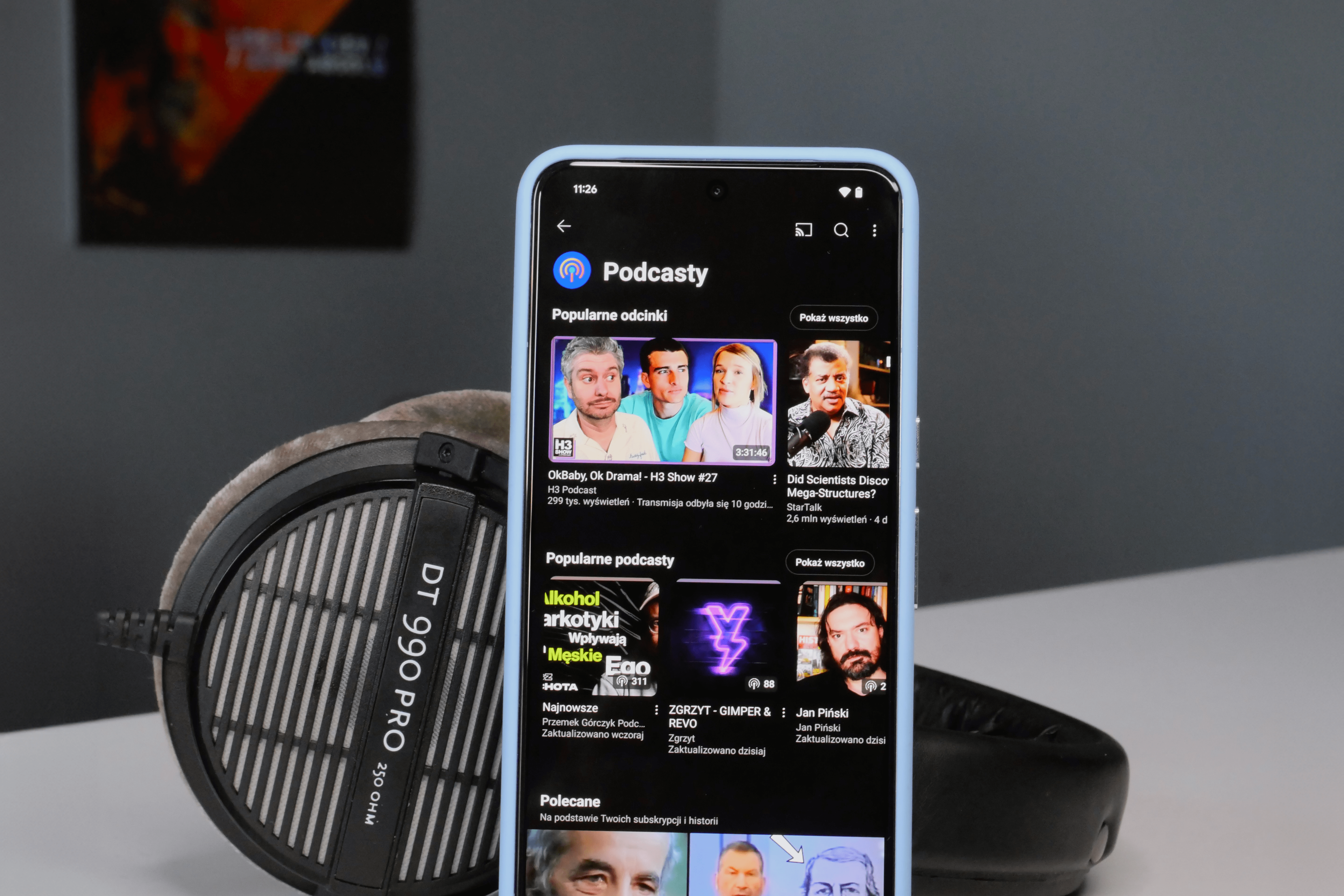 Smartfon z aplikacją podcastową wyświetlającą popularne odcinki.