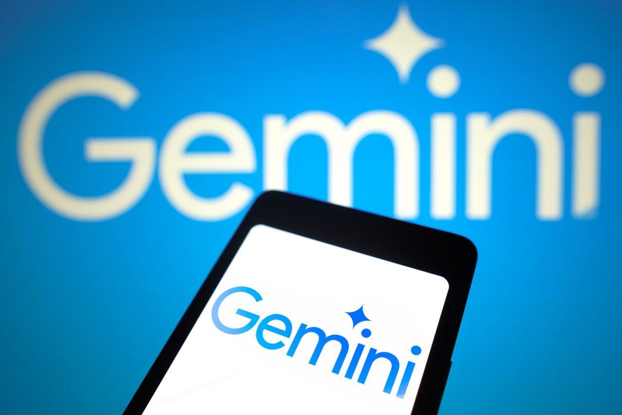 Logo Google Gemini na ekranie telefonu na tle tego samego logo na dużym ekranie.
