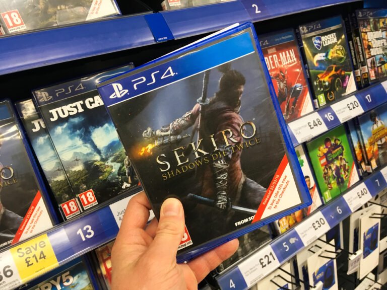 Osoba trzyma pudełko z grą "Sekiro: Shadows Die Twice" na dziale z grami PS4 w sklepie.