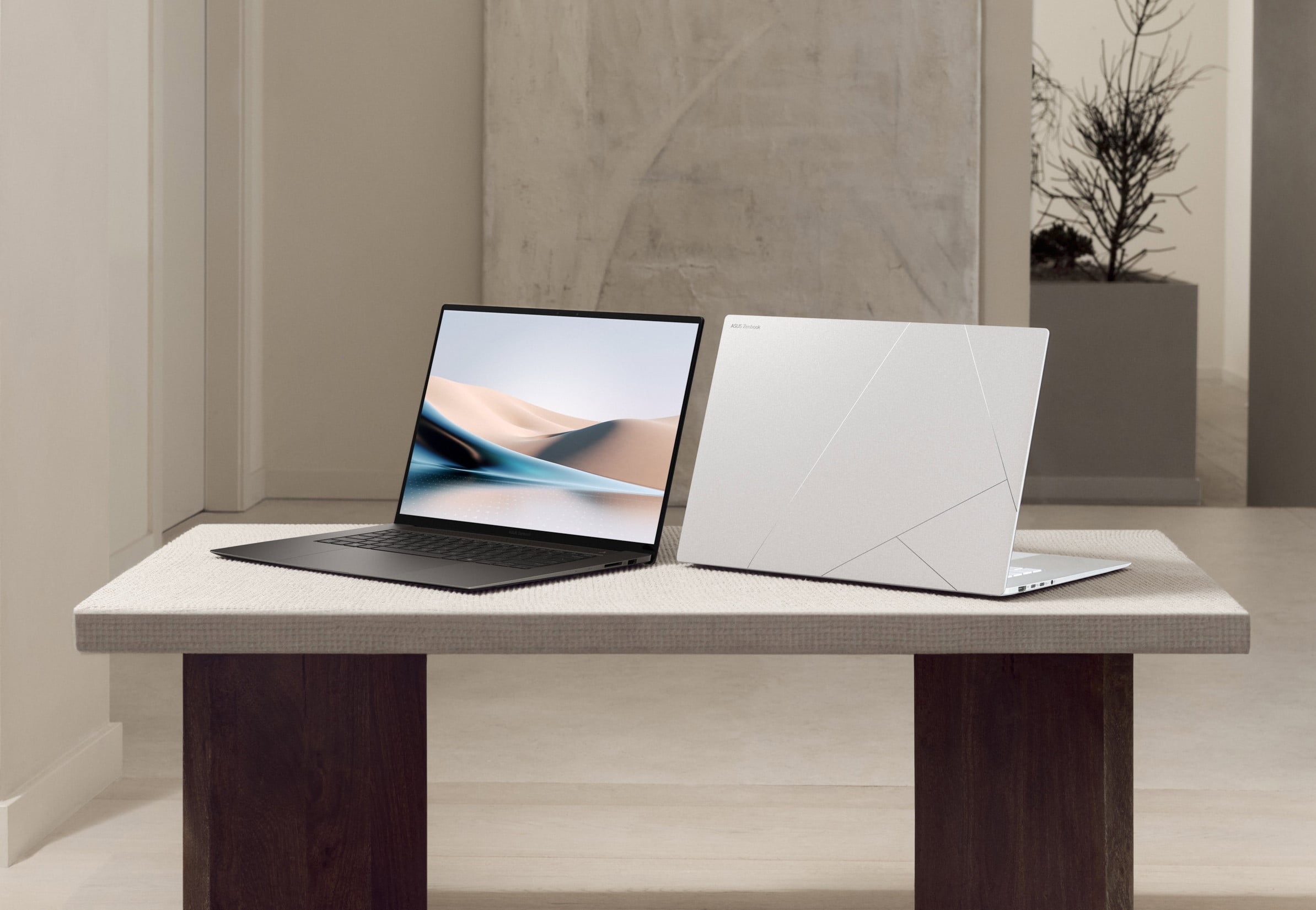 Dwa laptopy stojące na stole w nowoczesnym wnętrzu. Jeden z nich jest otwarty, a drugi zamknięty.