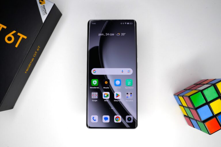 Smartfon realme GT 6T obok kostki Rubika i pudełka.