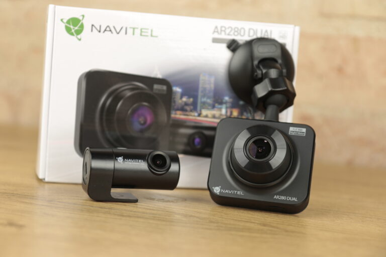 Recenzja Navitel AR280 Dual - kamera samochodowa i jej opakowanie na drewnianym tle.