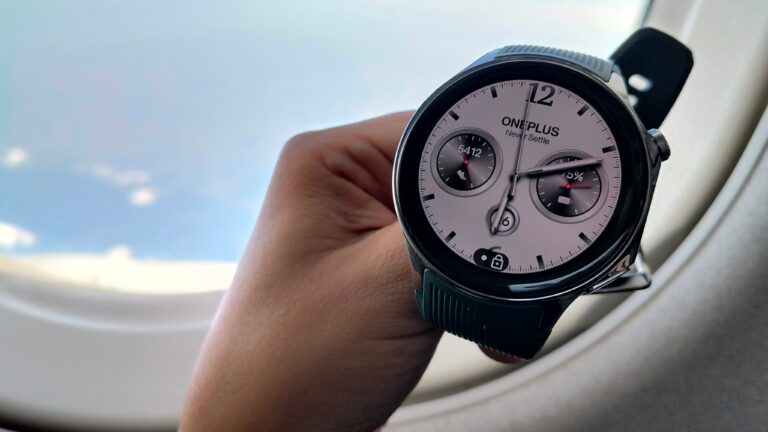 recenzja oneplus watch 2. Osoba trzymająca smartwatch OnePlus z okrągłym wyświetlaczem na tle okna samolotu.