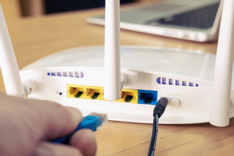 Osoba podłącza niebieski kabel internetowy do routera.